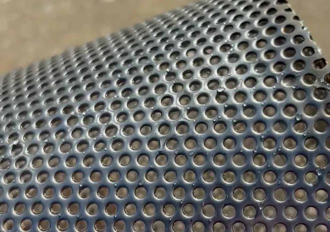 Close view of the round holes in a stainless steel skimmer basket.